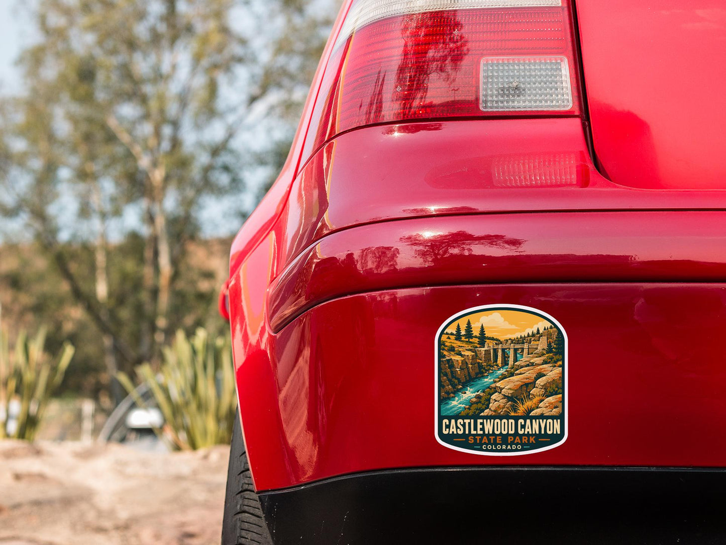 the rear end of a red car with a sticker on the back window that says "CASTLEWOOD CANYON COLORADO".