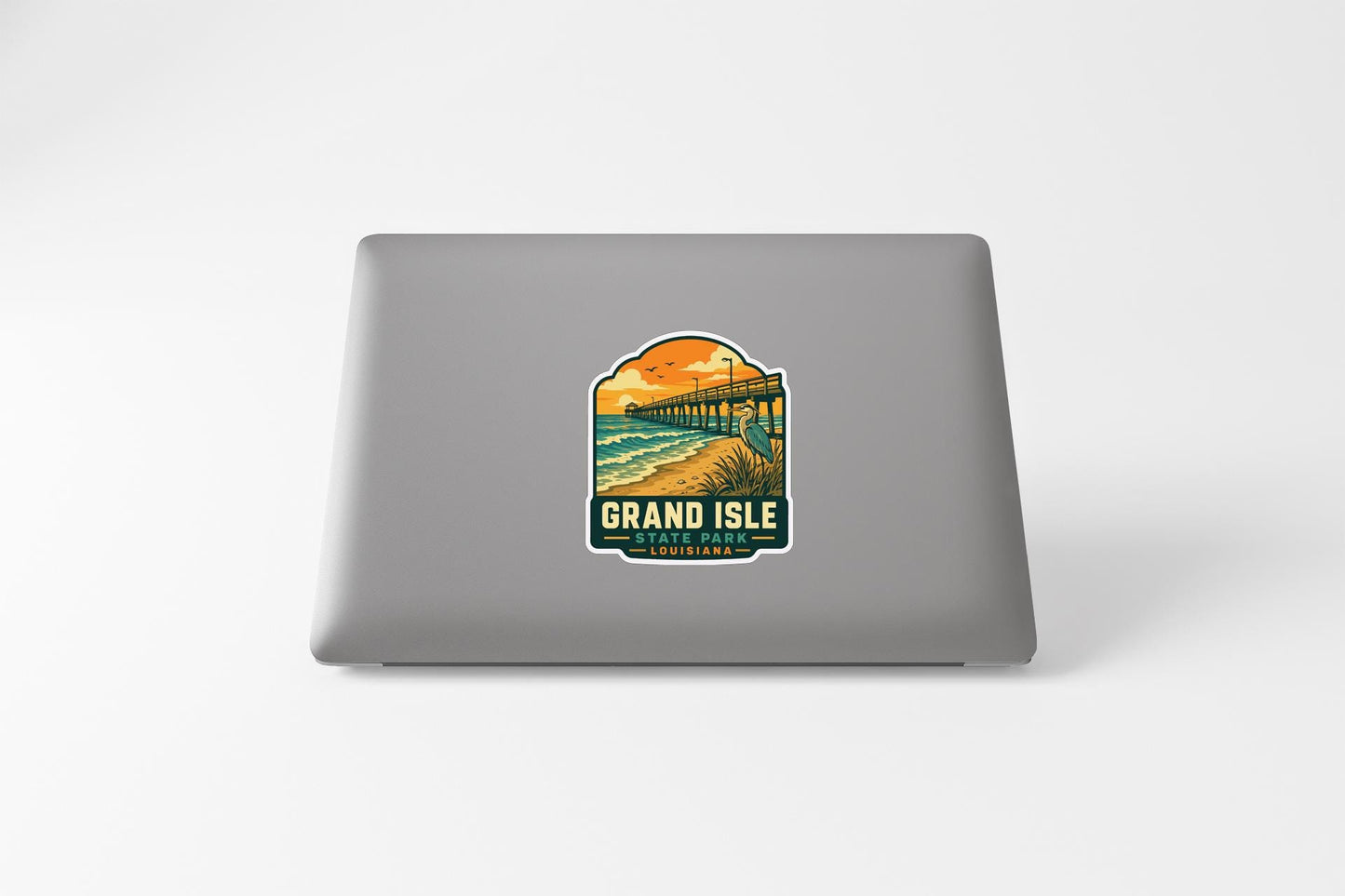 A sticker on the back of a laptop, depicting a scenic view of a beach and a pier.