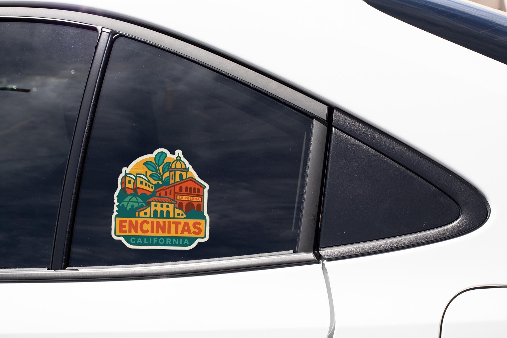 A sticker on the side of a car window, depicting a colorful illustration of a building with a palm tree and the text "ENCINITAS, CALIFORNIA".