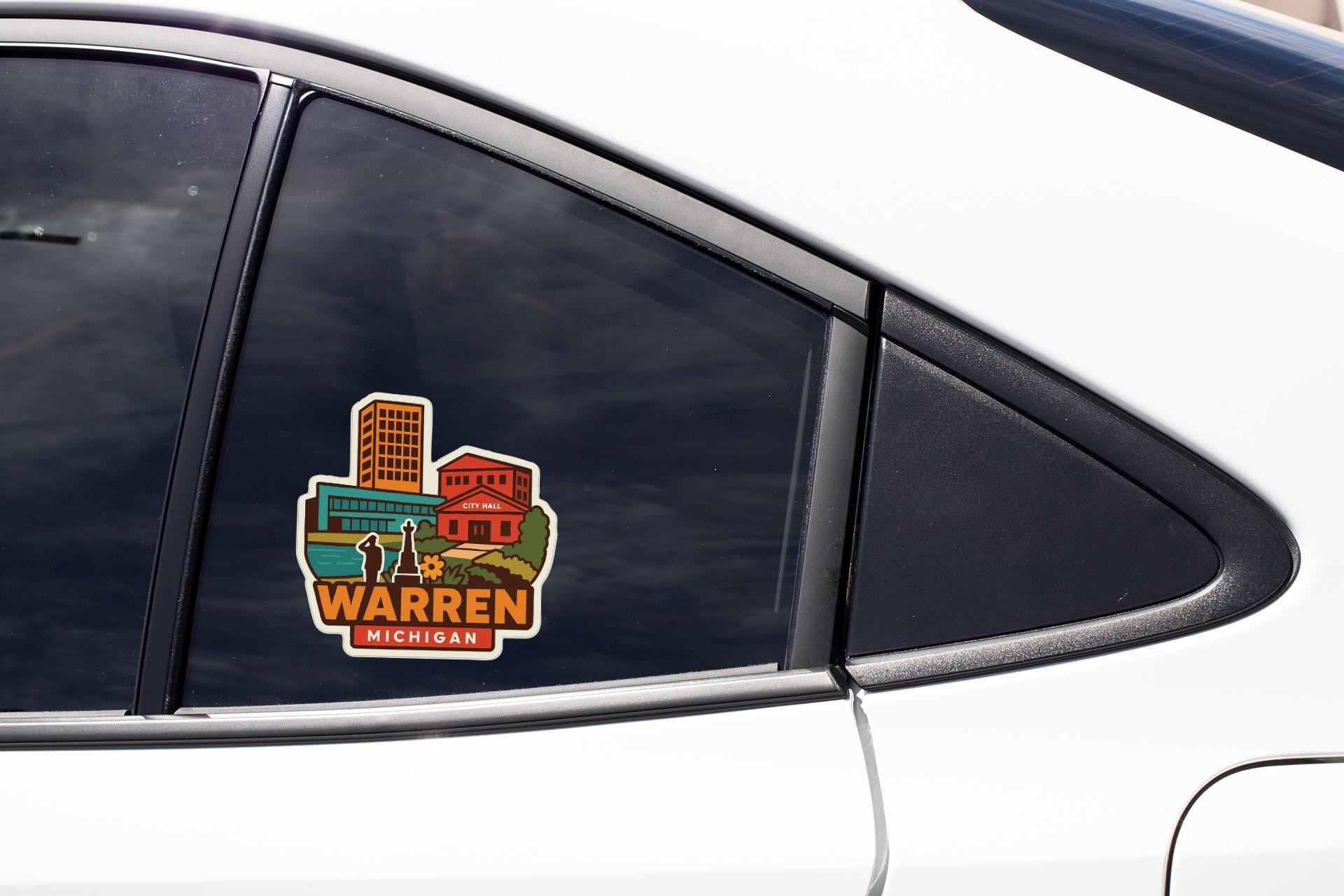 A sticker on the side of a car window, depicting a cityscape with buildings and a river.