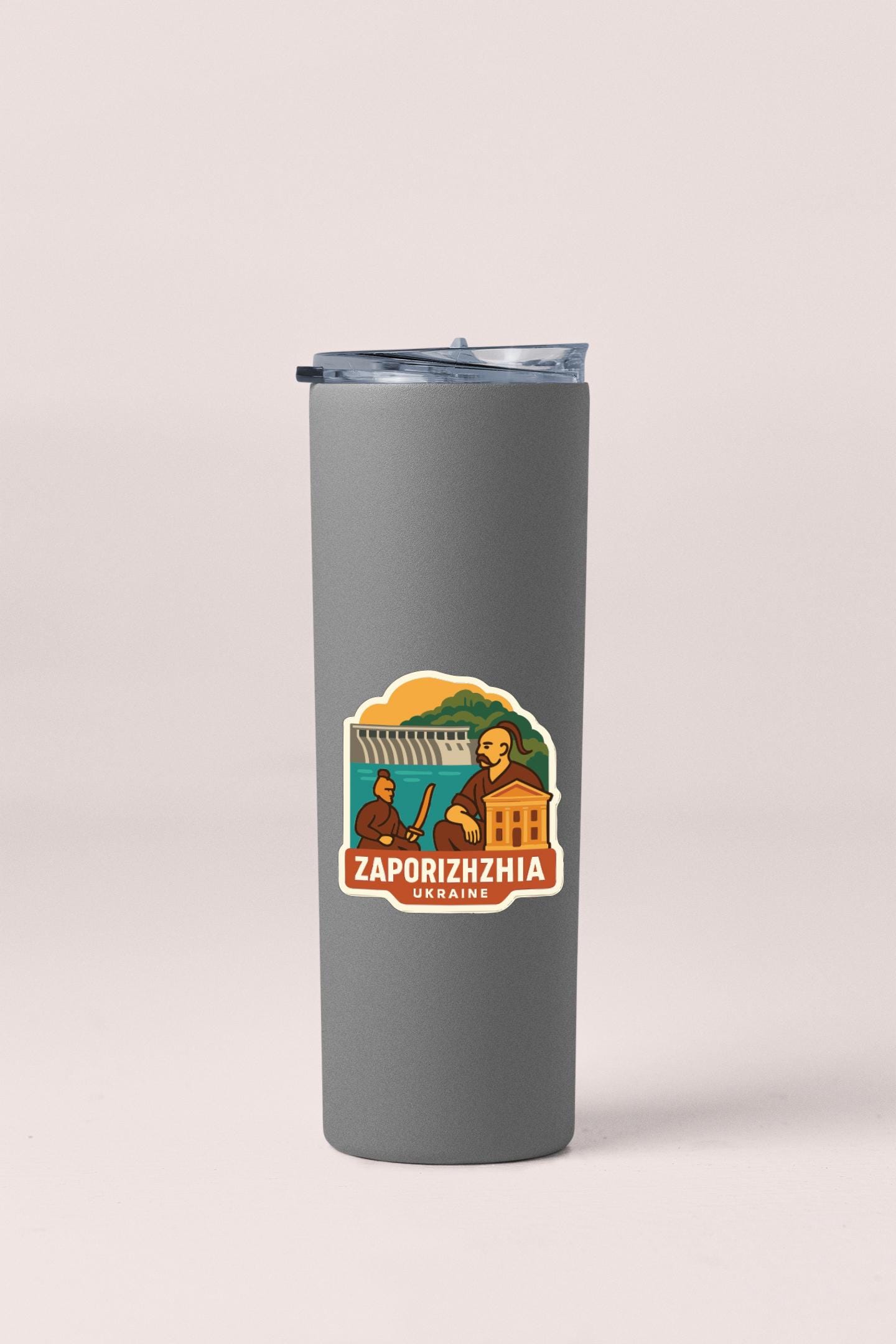 A gray insulated tumbler with a sticker depicting a person and a building, along with the text "ZAPORIZHZIA Ukraine".
