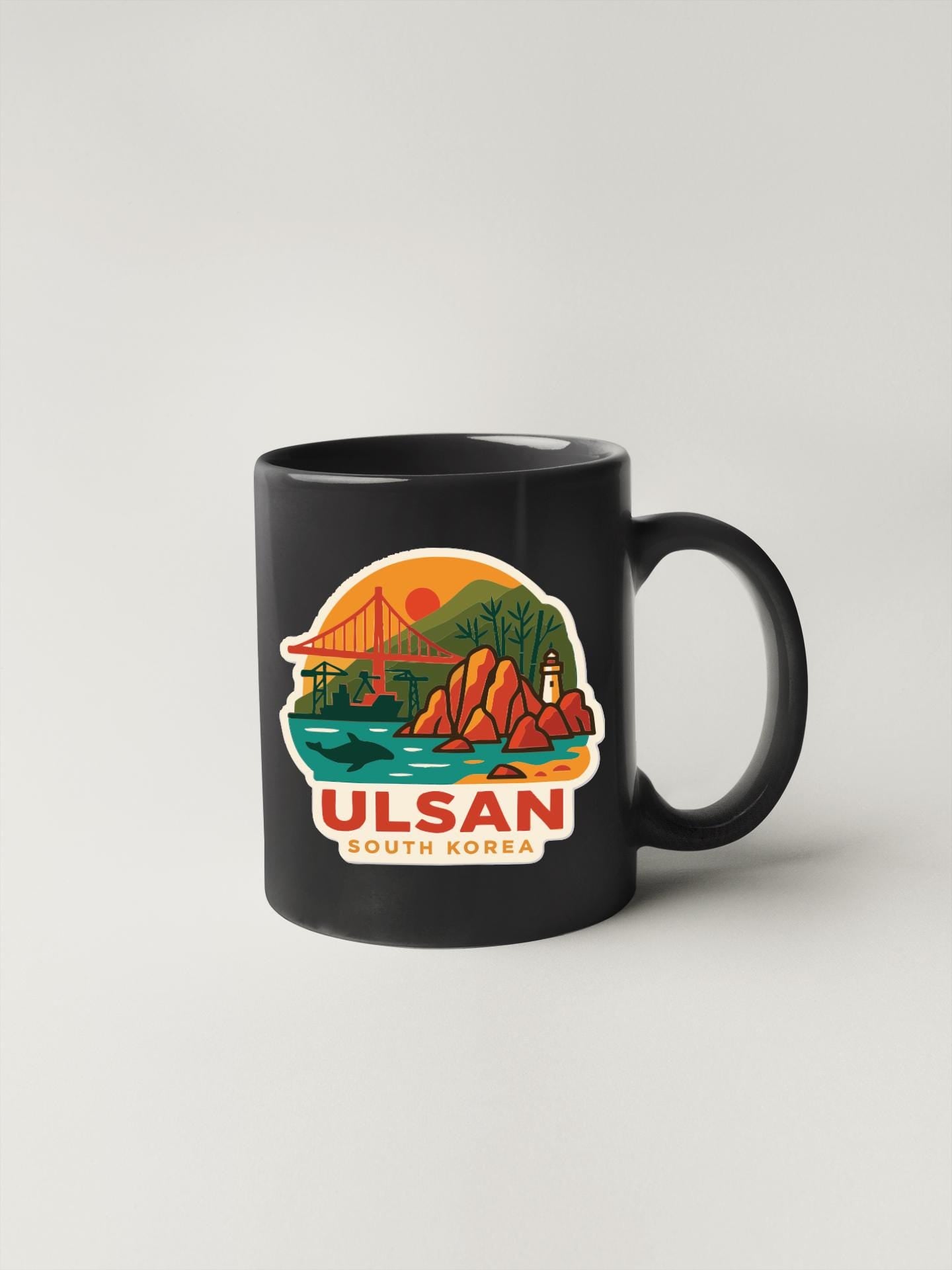 A black coffee mug with a colorful illustration depicting a scenic landscape, including a bridge, mountains, and a sunset.