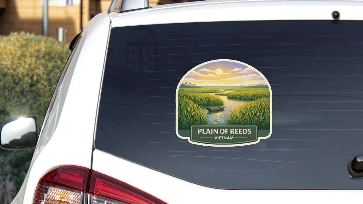A sticker on the rear window of a white car, depicting a scenic landscape with a river, a boat, and a sunset.