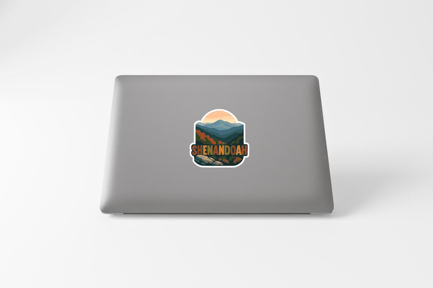 A sticker on the back of a laptop displaying the text "SHENANDOAH" and an illustration of mountains and a sunset.