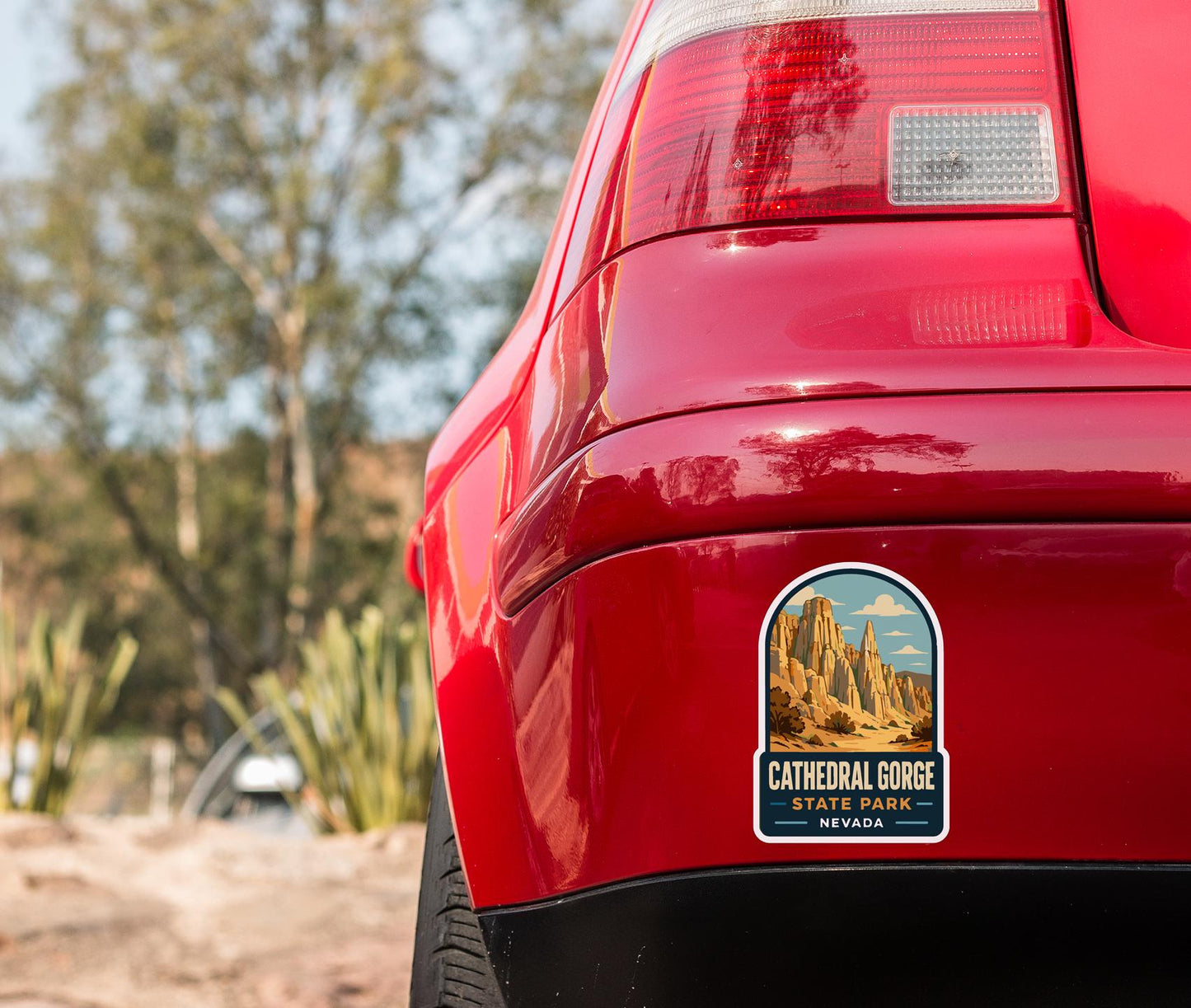 the rear end of a red car with a sticker on the back window that reads "CATHEDRAL GORGE STATE PARK NEVADA".
