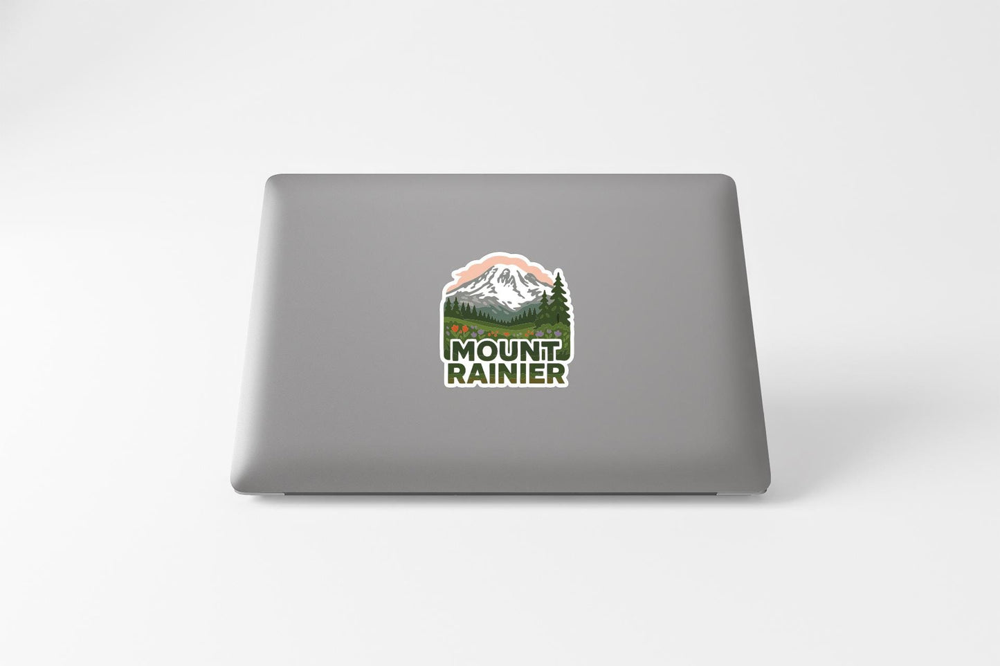 a sticker with a mountain landscape and the text "MOUNT RAINIER" on the back of a laptop.