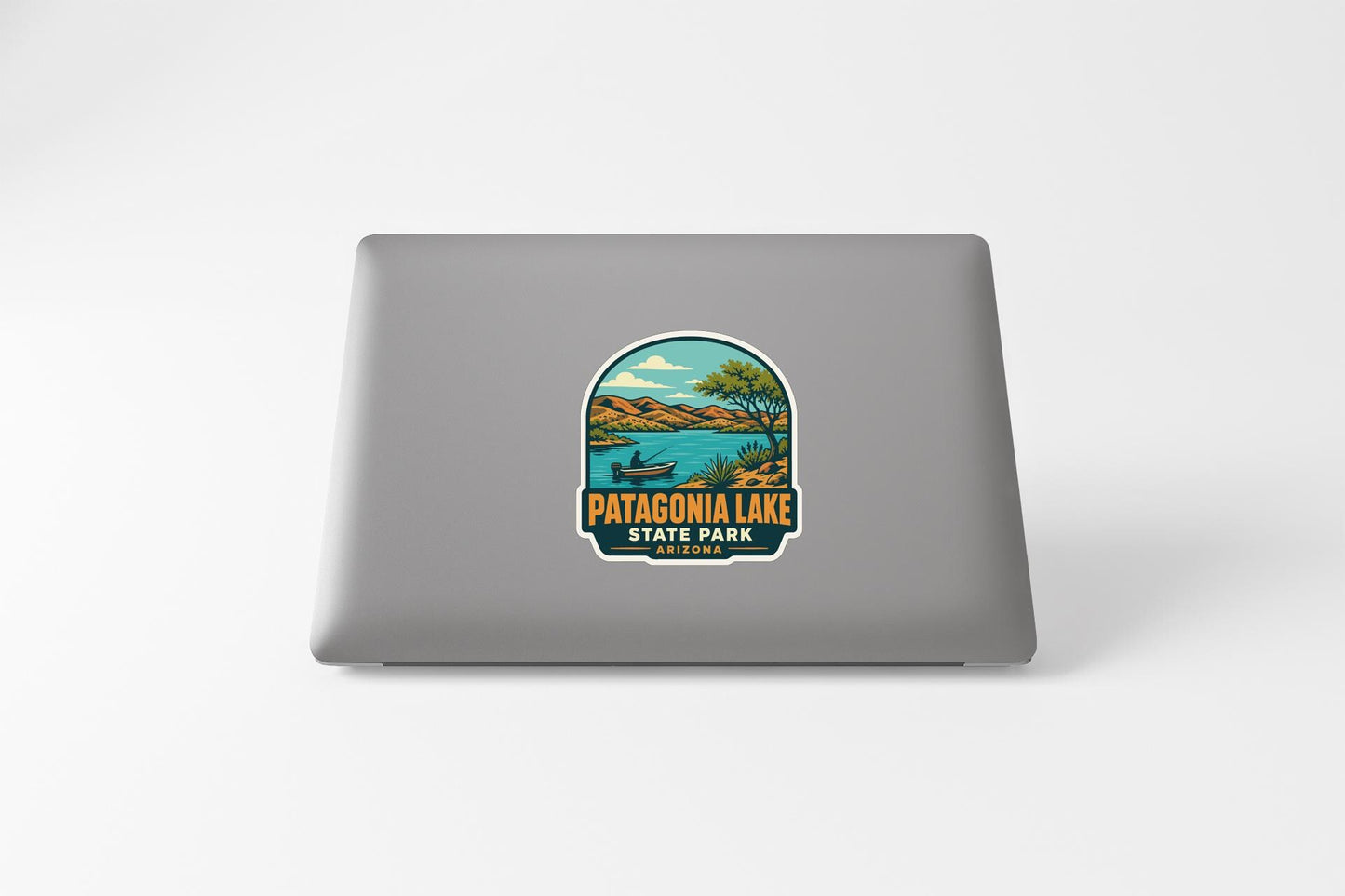 A sticker on the back of a laptop, depicting a scenic landscape with Patagonia Lake and the State Park logo.
