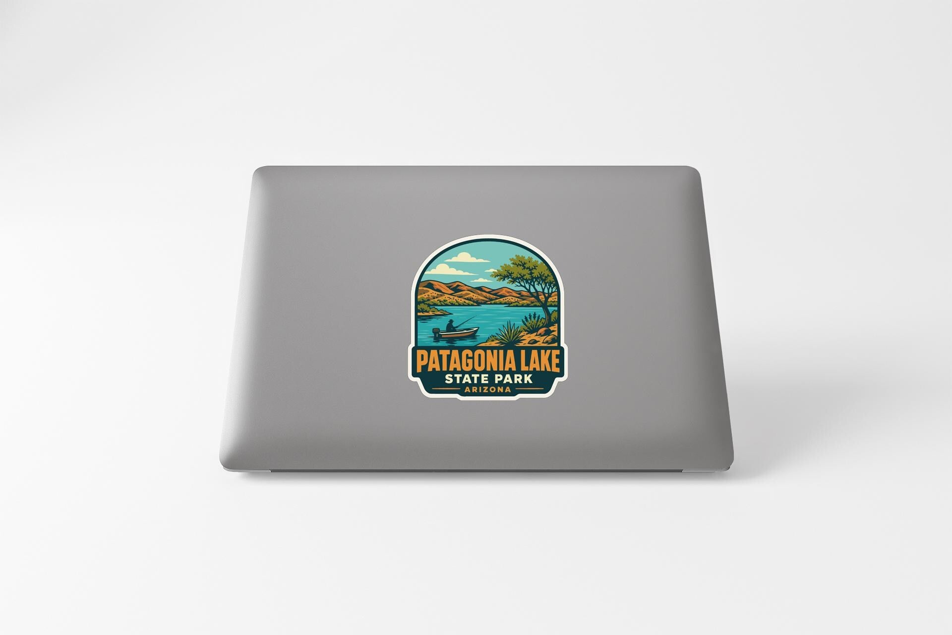 A sticker on the back of a laptop, depicting a scenic landscape with Patagonia Lake and the State Park logo.