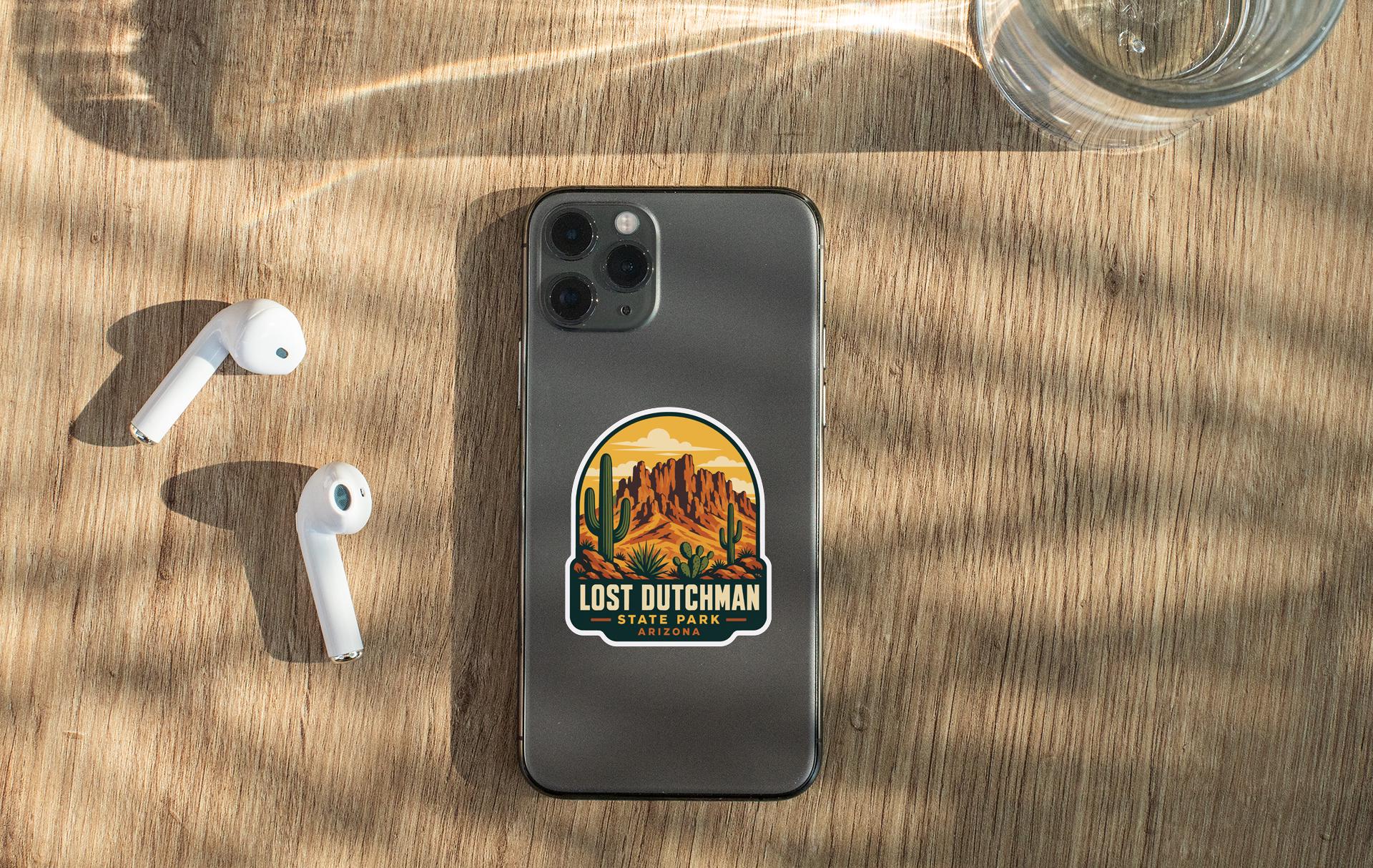 a smartphone with a sticker on it, placed on a wooden surface alongside a pair of white earbuds and a glass of water.