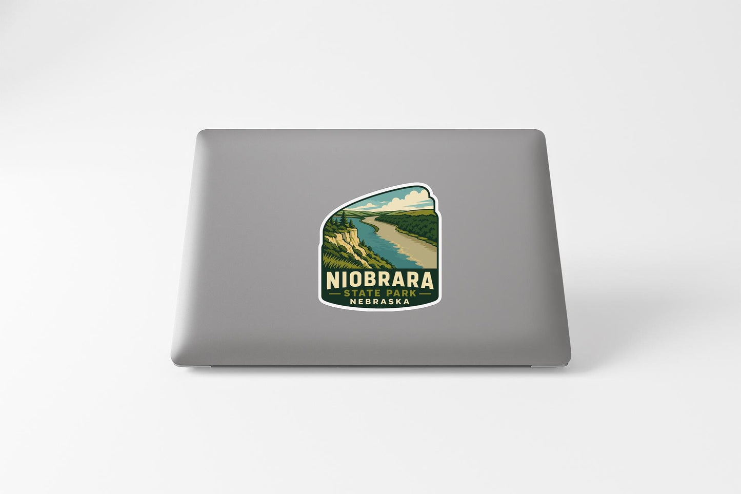 A sticker on the back of a laptop displaying a scenic landscape with a river and mountains.