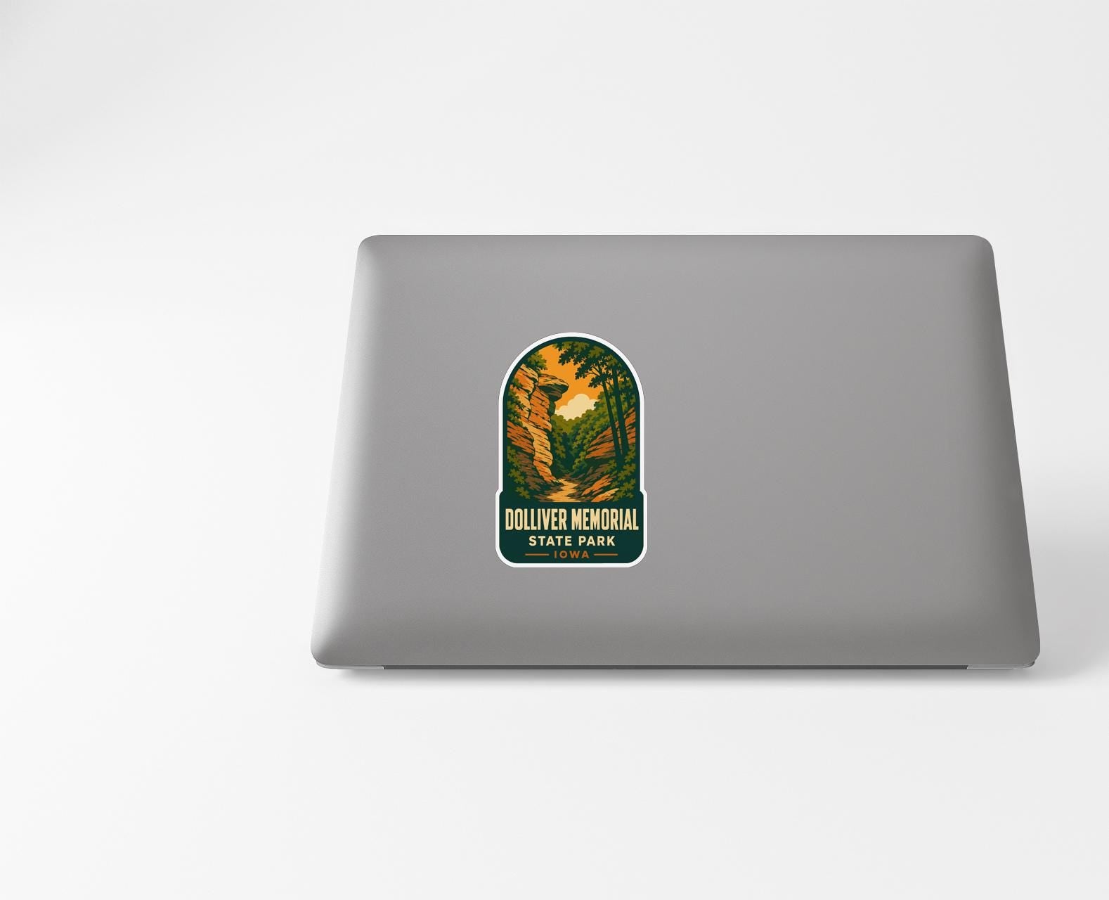 A sticker with a scenic landscape depicting a forest and a mountain range, with the text "Dolliver Memorial State Park" printed on it.