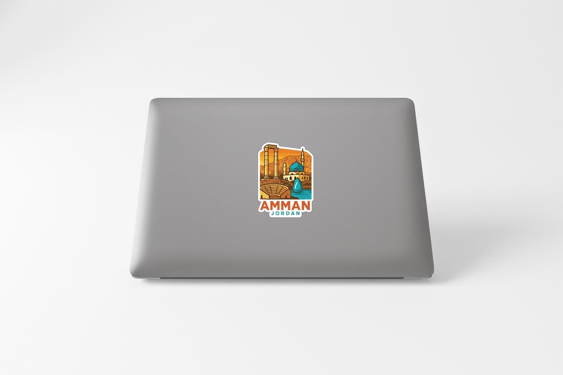 a sticker with an illustration of a building and the text "AMMAN JORDAN" on the back of a laptop.