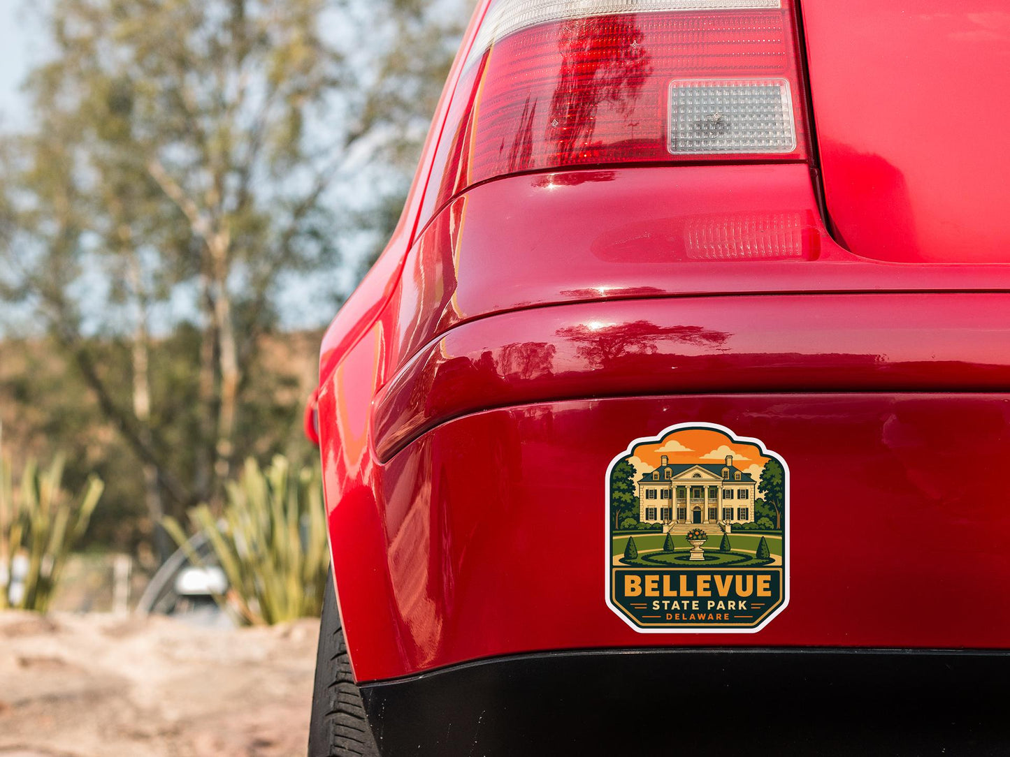 the rear end of a red car with a sticker on the trunk that reads "Bellevue State Park, California".