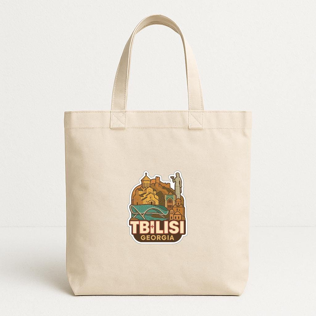 A beige tote bag with a printed design featuring the city of Tbilisi, Georgia.