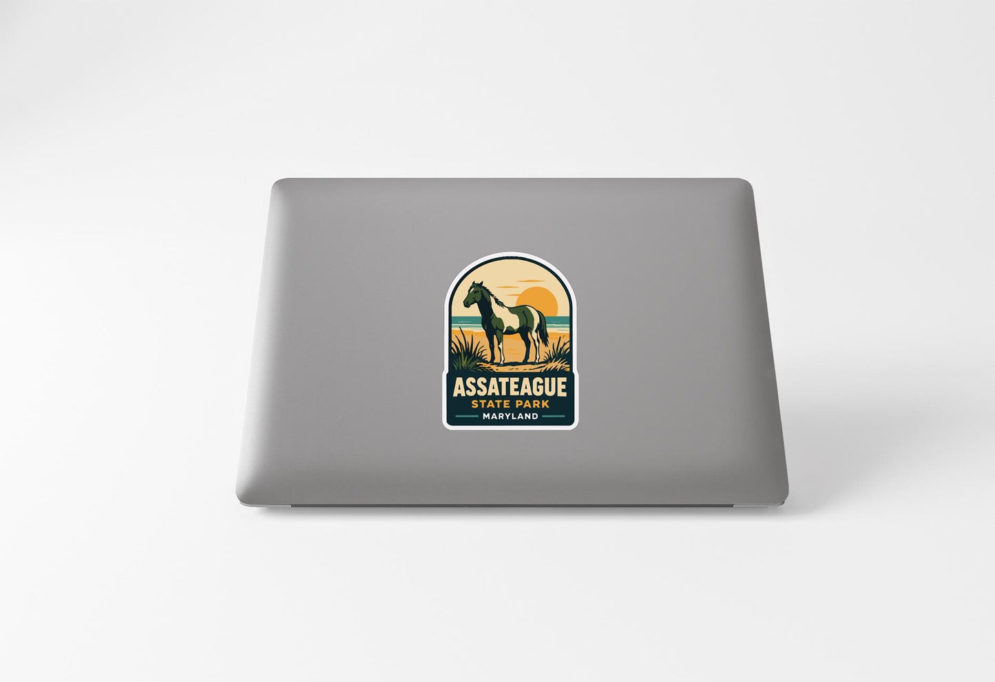 a sticker on the back of a laptop with a horse and a sunset in the background.