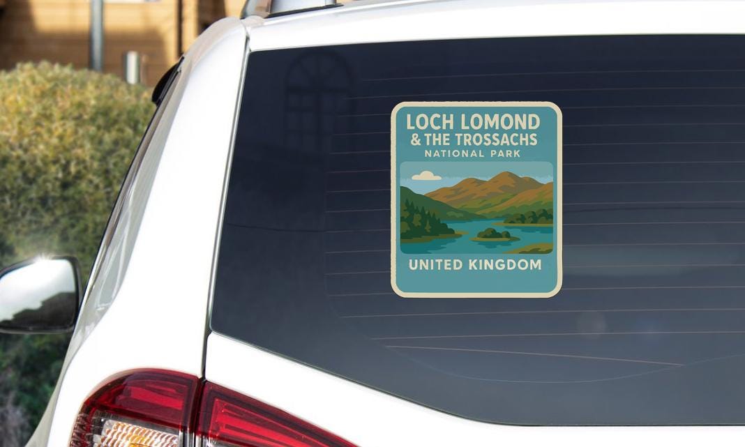 A sticker on the rear window of a car, depicting a scenic landscape with mountains and a lake, along with the text "Loch Lomond & the Trossachs National Park United Kingdom".