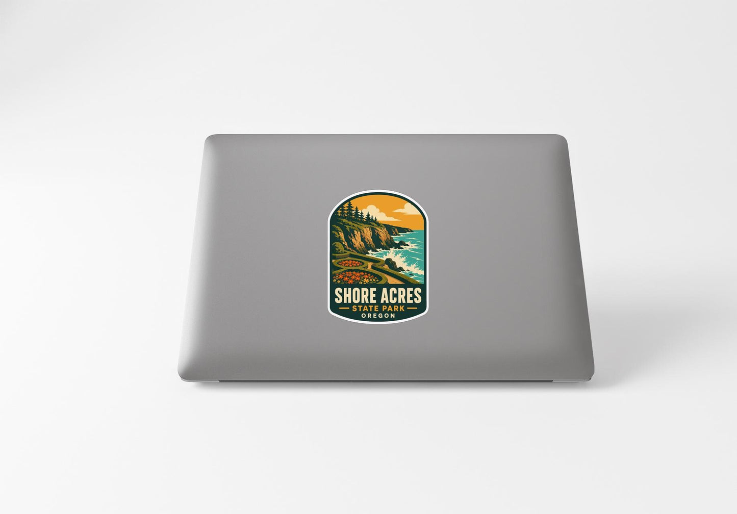 a sticker with a scenic landscape of a cliff overlooking the ocean, with the text "SHORE ACRES STATE PARK" printed on it.
