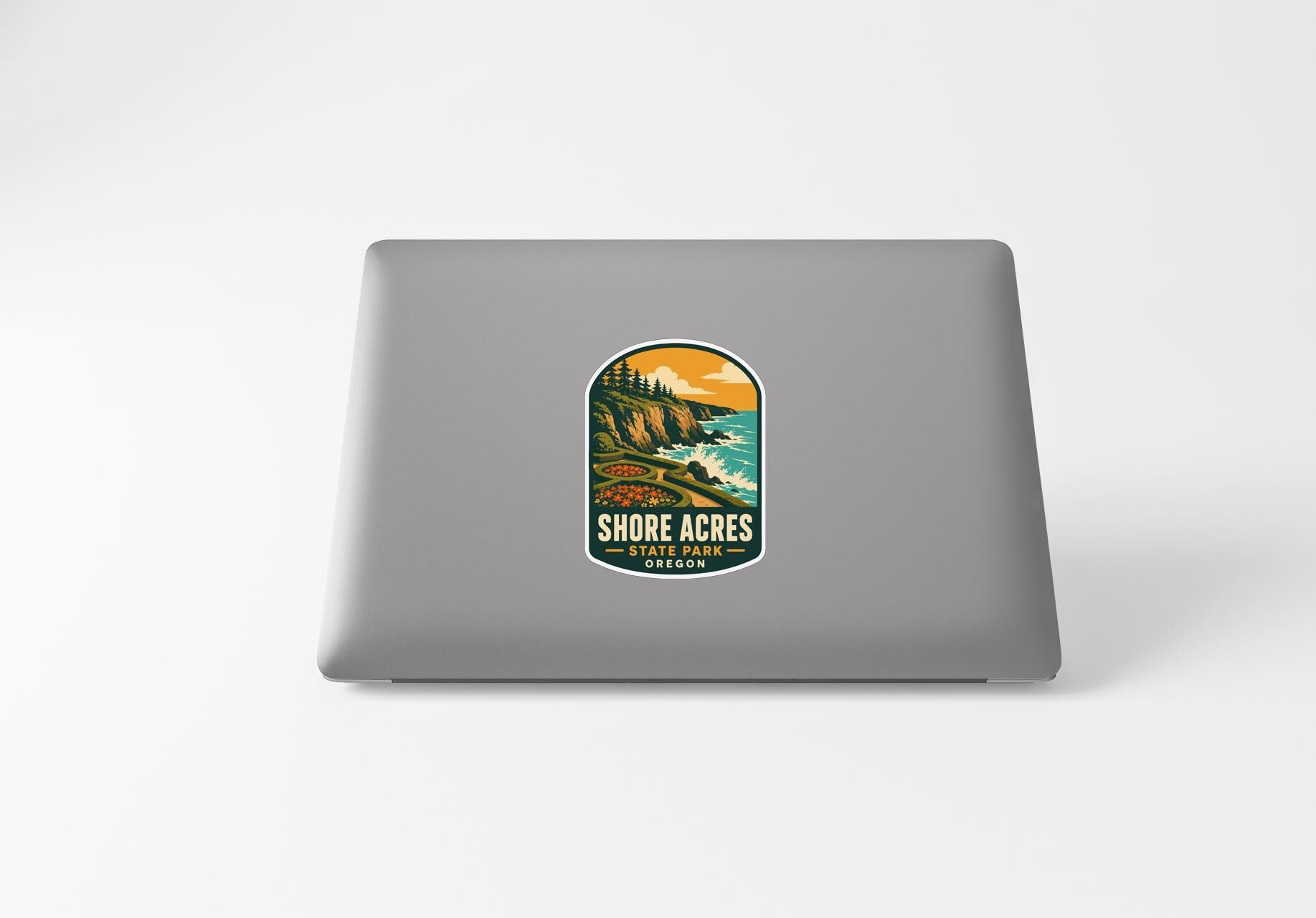 a sticker with a scenic landscape of a cliff overlooking the ocean, with the text "SHORE ACRES STATE PARK" printed on it.