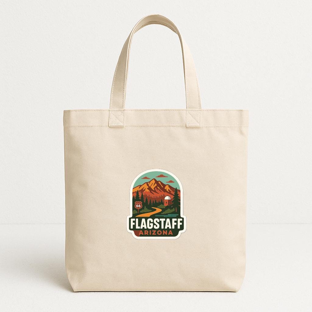 A beige tote bag with a printed design featuring mountains and a road, along with the text "FLAGSTAFF ARIZONA".