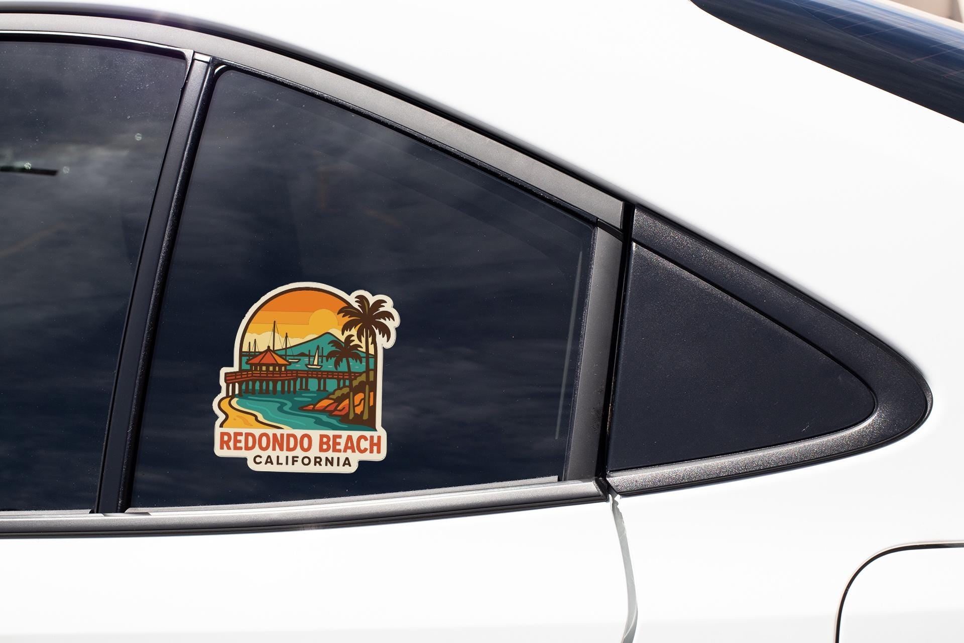 A sticker on the side of a car window, depicting a beach scene with palm trees and a sunset.