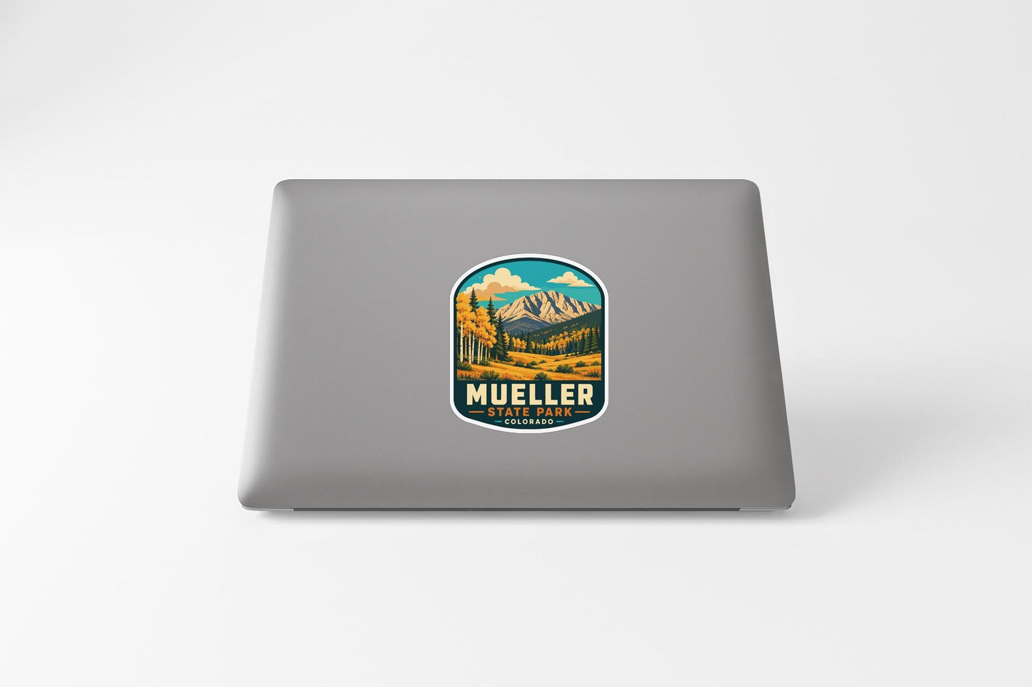 a sticker with a mountain landscape and the text "MUELLER STATE PARK" on a laptop.