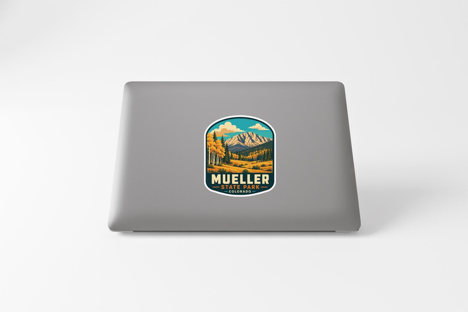 a sticker with a mountain landscape and the text "MUELLER STATE PARK" on a laptop.