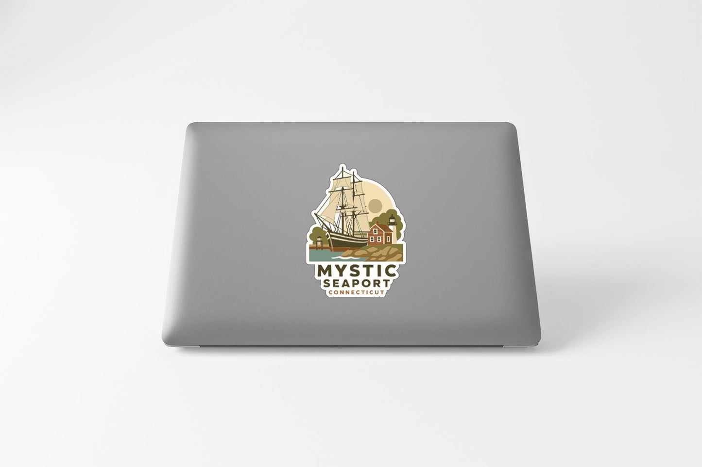 a sticker on the back of a laptop that displays a ship and a lighthouse, along with the text "MYSTIC SEAPORT CONNECTICUT".