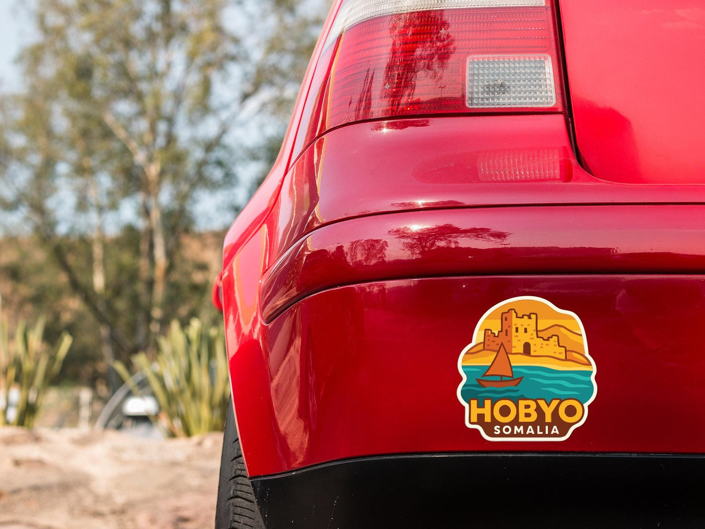 the rear end of a red car with a sticker on the trunk that says "HOBBYO SOMALIA".