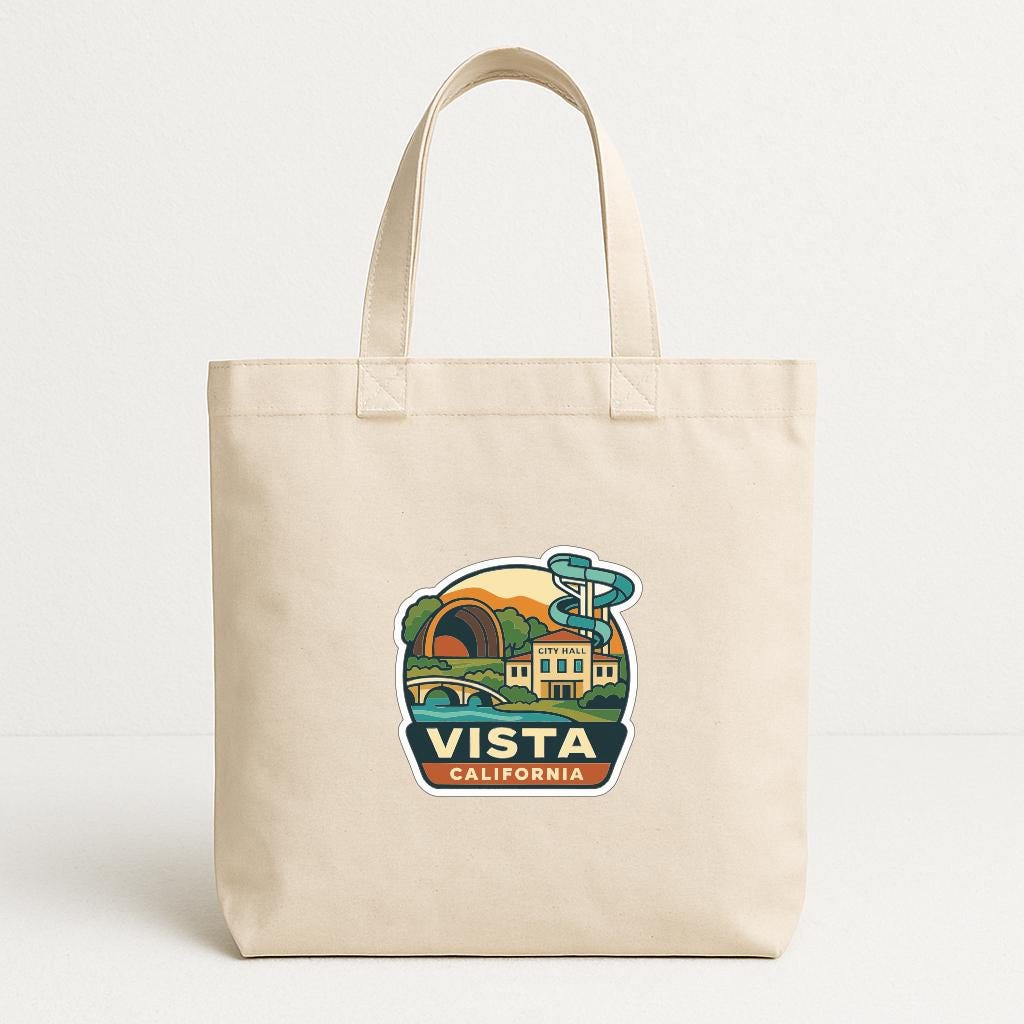 A beige tote bag with a printed design depicting a scenic view of Vista, California.