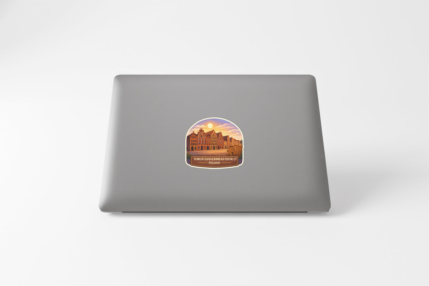 a sticker on the back of a laptop, depicting a building with a sunset in the background.