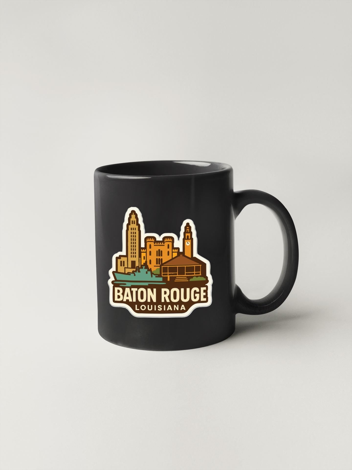 A black coffee mug with a sticker depicting the city of Baton Rouge, Louisiana.