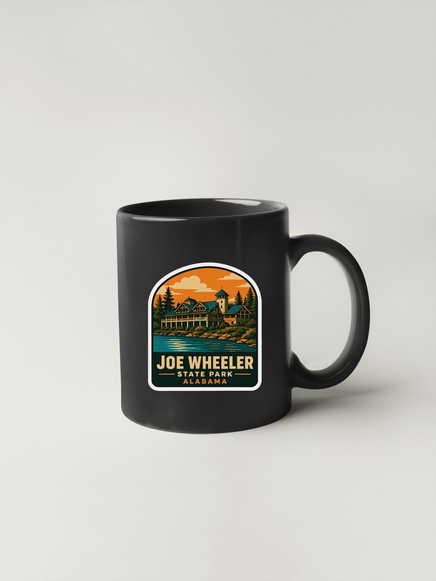 A black coffee mug with a graphic design depicting a scenic landscape, including a building and trees, along with the text "Joe Wheeler State Park Albertson".
