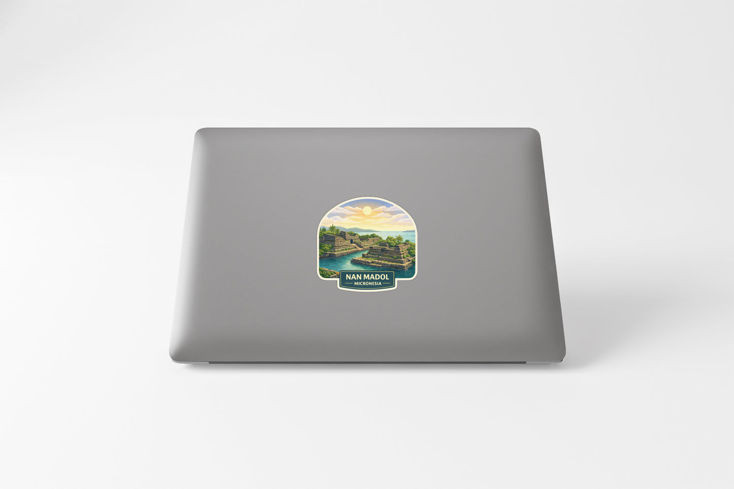 A sticker depicting a scenic landscape with a river and mountains, placed on the back of a laptop computer.