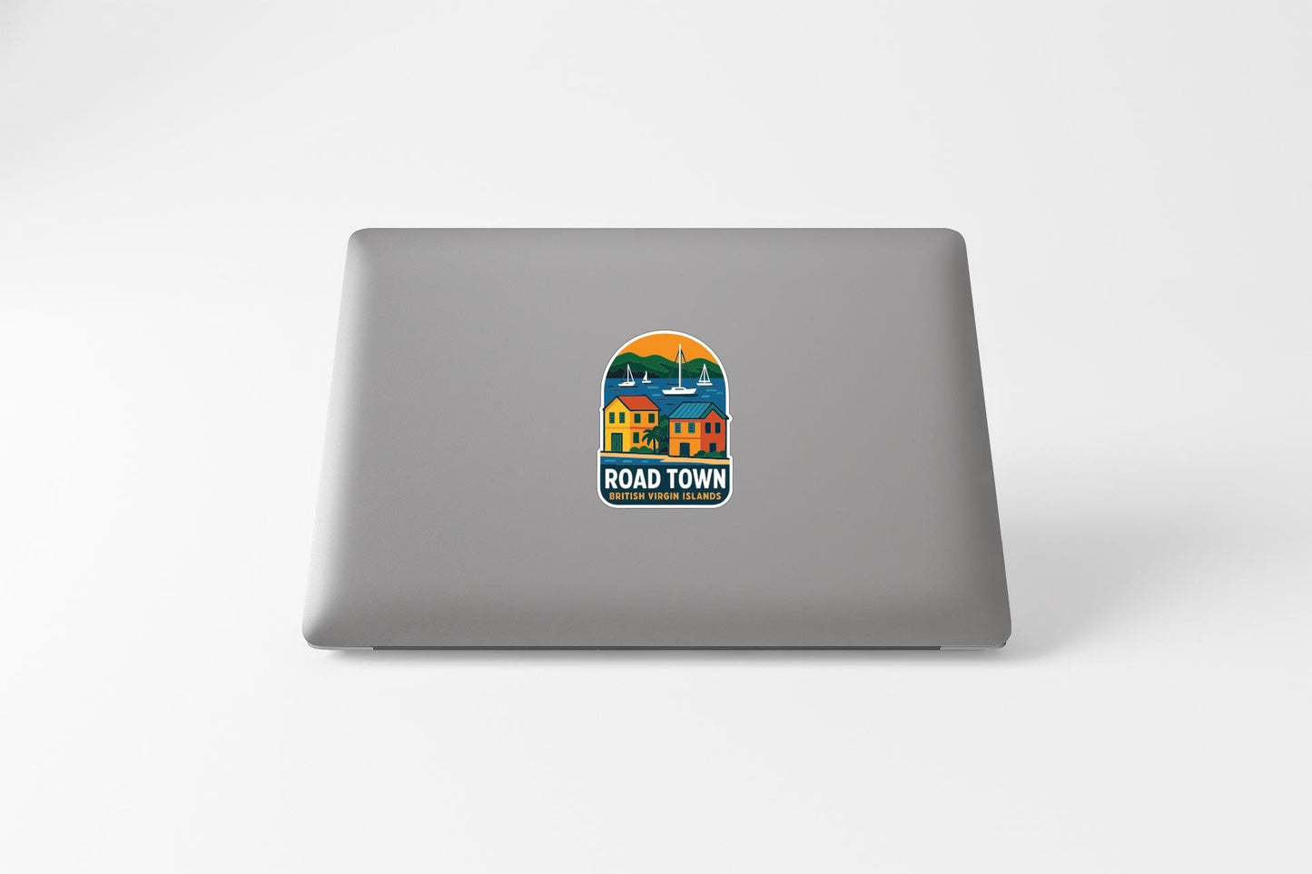a sticker on the back of a laptop that says "ROAD TOWN" and includes a colorful illustration of a small town.