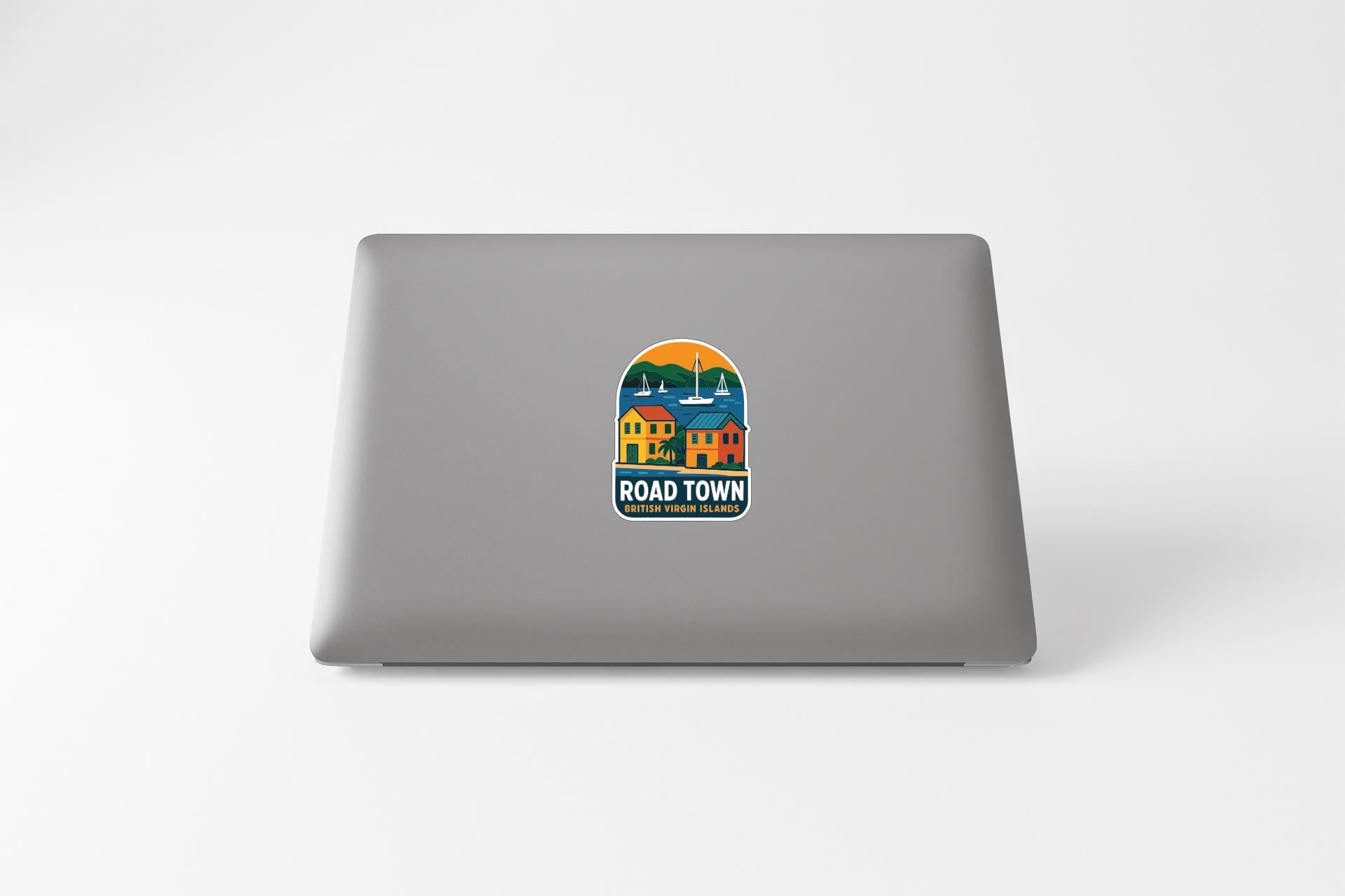 a sticker on the back of a laptop that says "ROAD TOWN" and includes a colorful illustration of a small town.