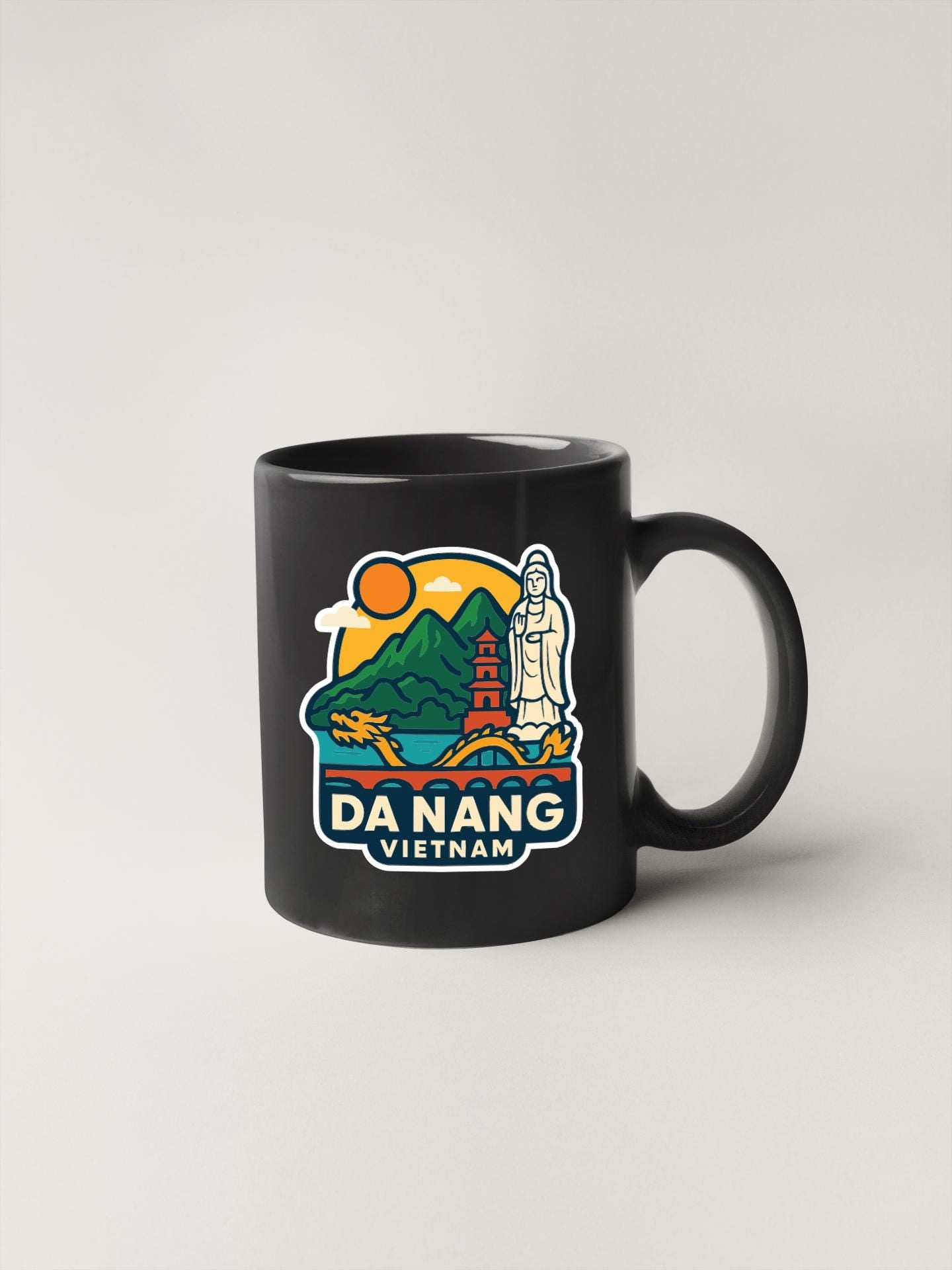 A black coffee mug with a colorful illustration depicting a scenic view of Da Nang, Vietnam.