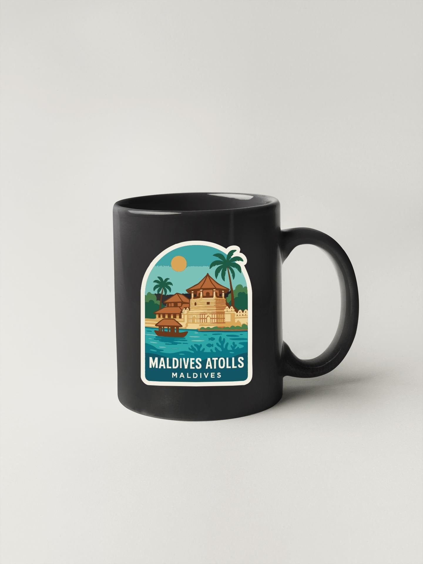 A black coffee mug with a tropical island scene and palm trees printed on it, along with the text "Maldives Atolls" printed below.