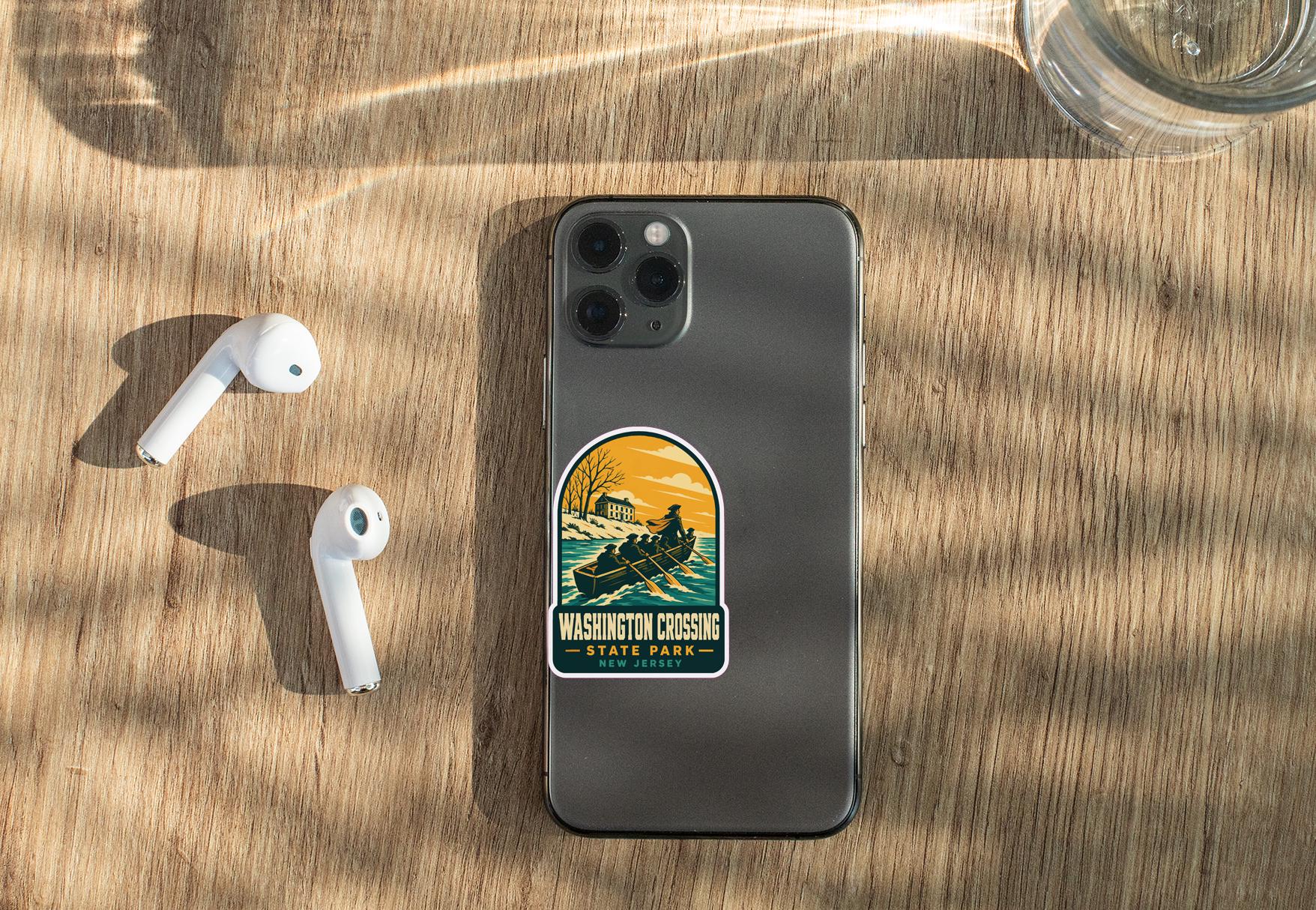 a smartphone with a sticker on it, placed on a wooden surface alongside a pair of white earbuds and a glass of water.
