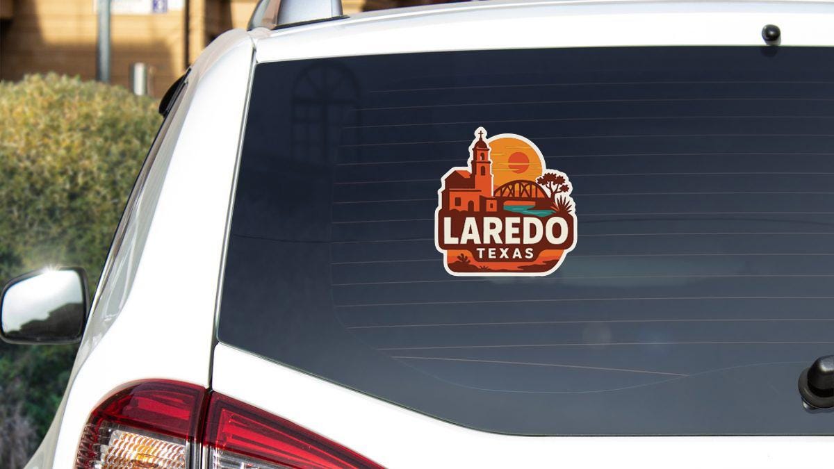 A sticker on the rear window of a white car that says "Laredo, Texas".