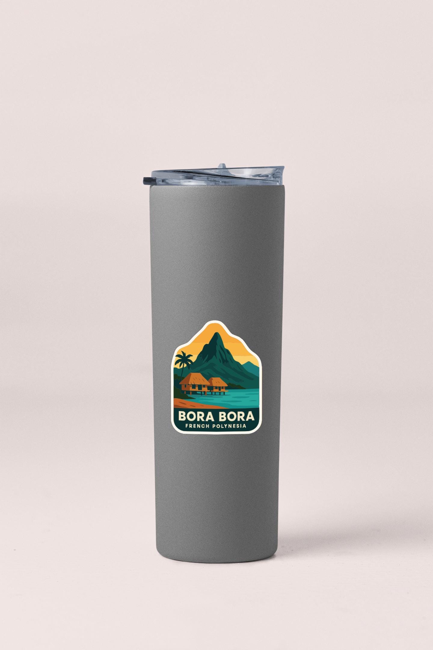 A gray insulated tumbler with a sticker depicting a tropical island landscape.