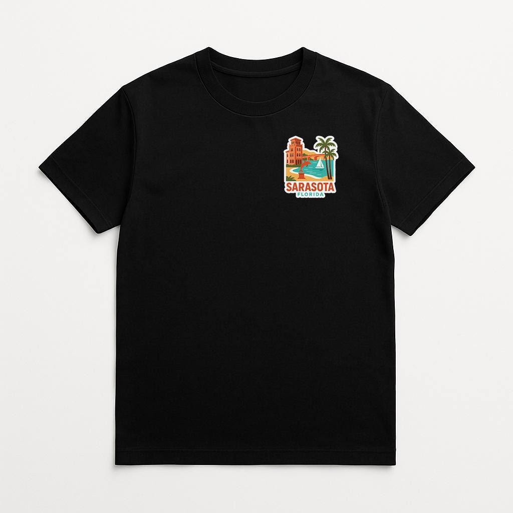 A black t-shirt with a graphic design depicting a beach scene and the text "SARASOTA FLORIDA" printed on it.