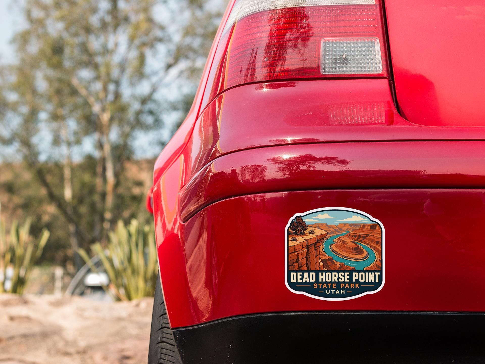 the rear end of a red car with a sticker on the back window that reads "Dead Horse Point State Park Utah".