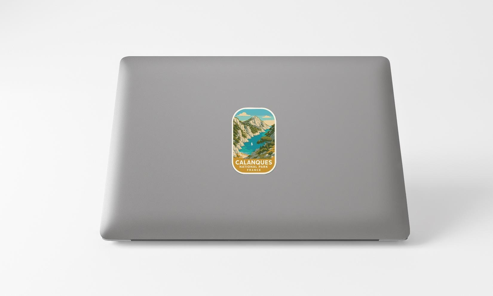 A sticker depicting a scenic mountain landscape with a river is affixed to the back of a laptop computer.