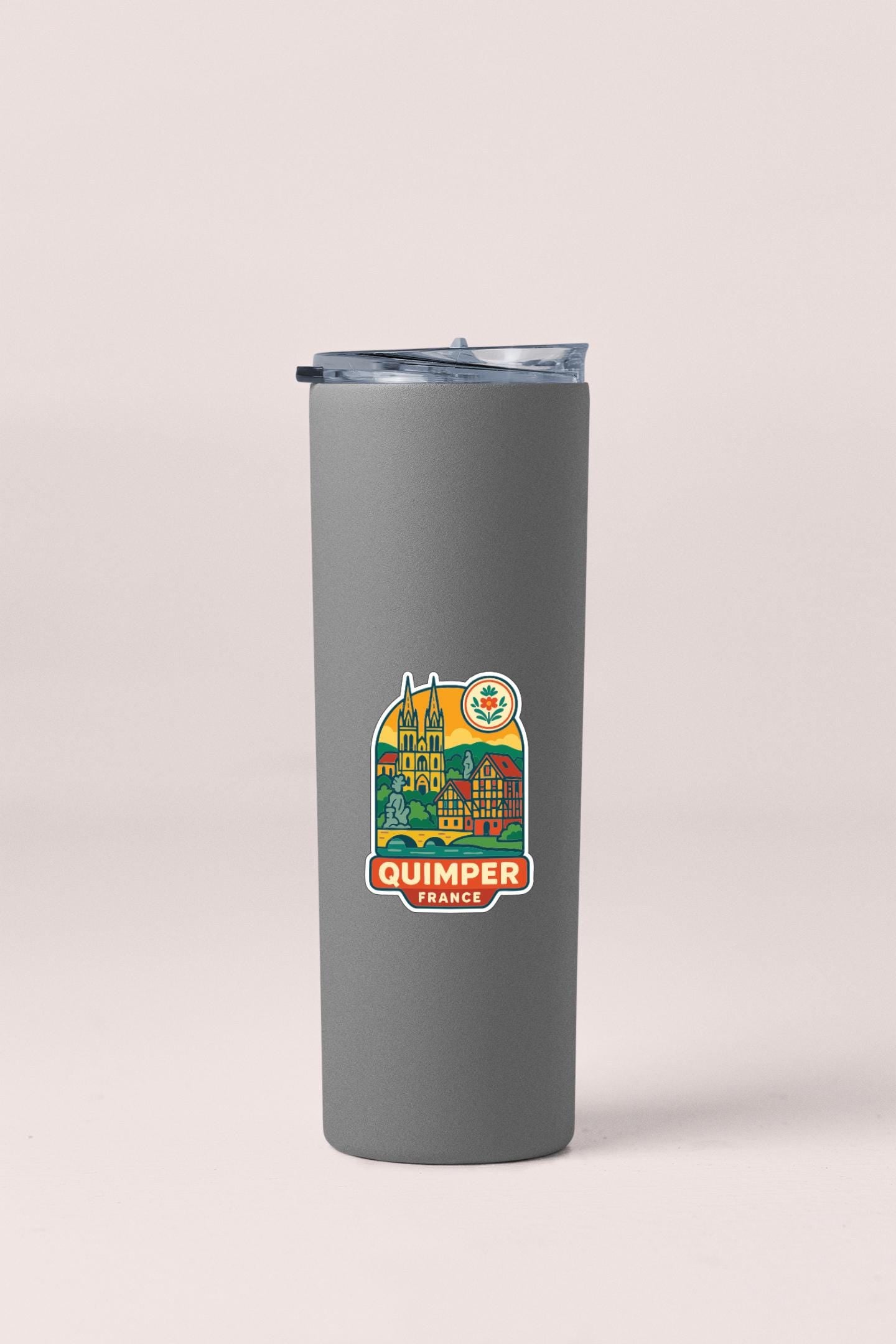 A gray insulated tumbler with a sticker depicting a cityscape and the text "Quimper, France" printed on it.
