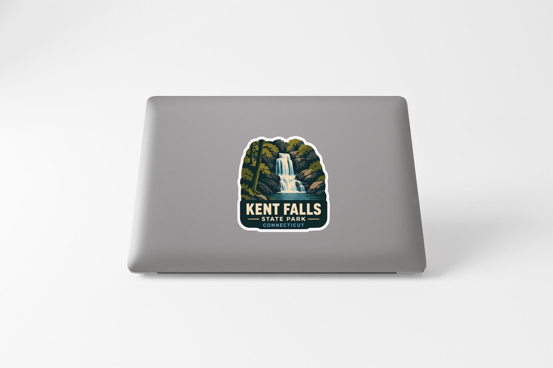 A sticker on the back of a laptop, depicting a waterfall surrounded by trees and foliage.