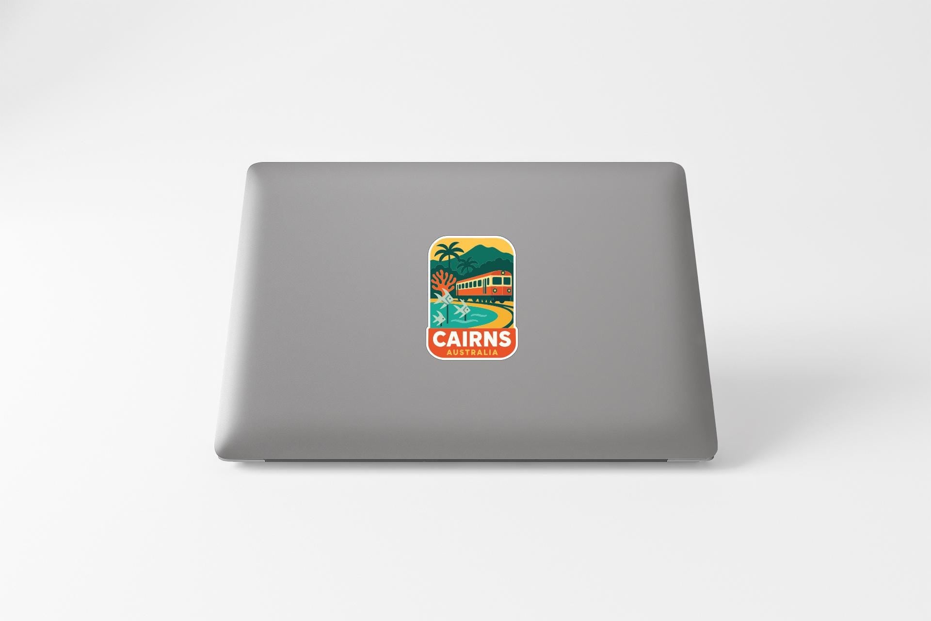 a sticker with a tropical beach scene and the word "CAIRNS" printed on a laptop.