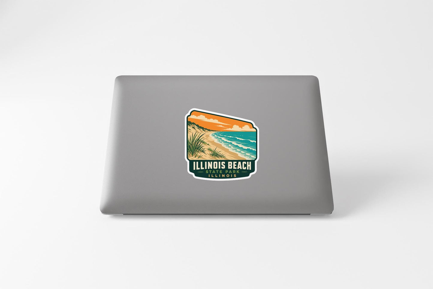 A sticker on the back of a laptop, depicting a beach scene with a sunset and palm trees.