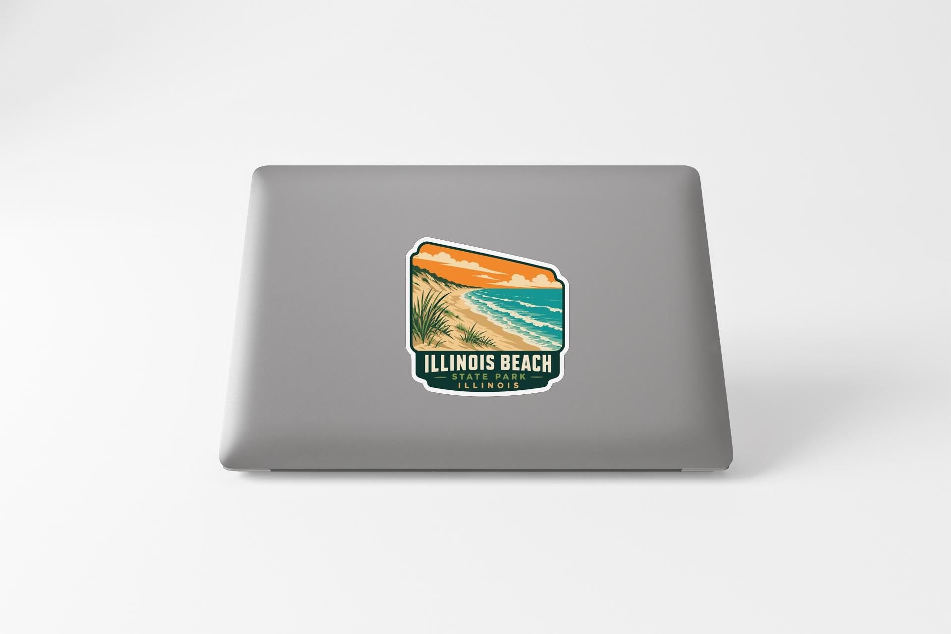 A sticker on the back of a laptop, depicting a beach scene with a sunset and palm trees.