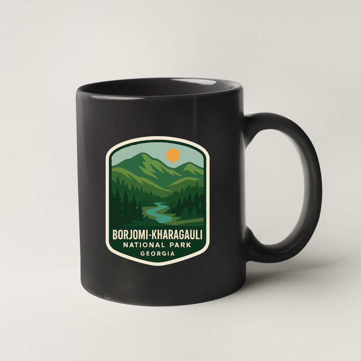 A black coffee mug with a label that says "BORJOMI-KHARAGALI NATIONAL PARK GEORGIA".