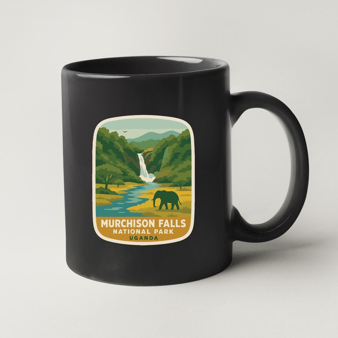 A black coffee mug with a label that features an illustration of Murchison Falls National Park in Uganda.